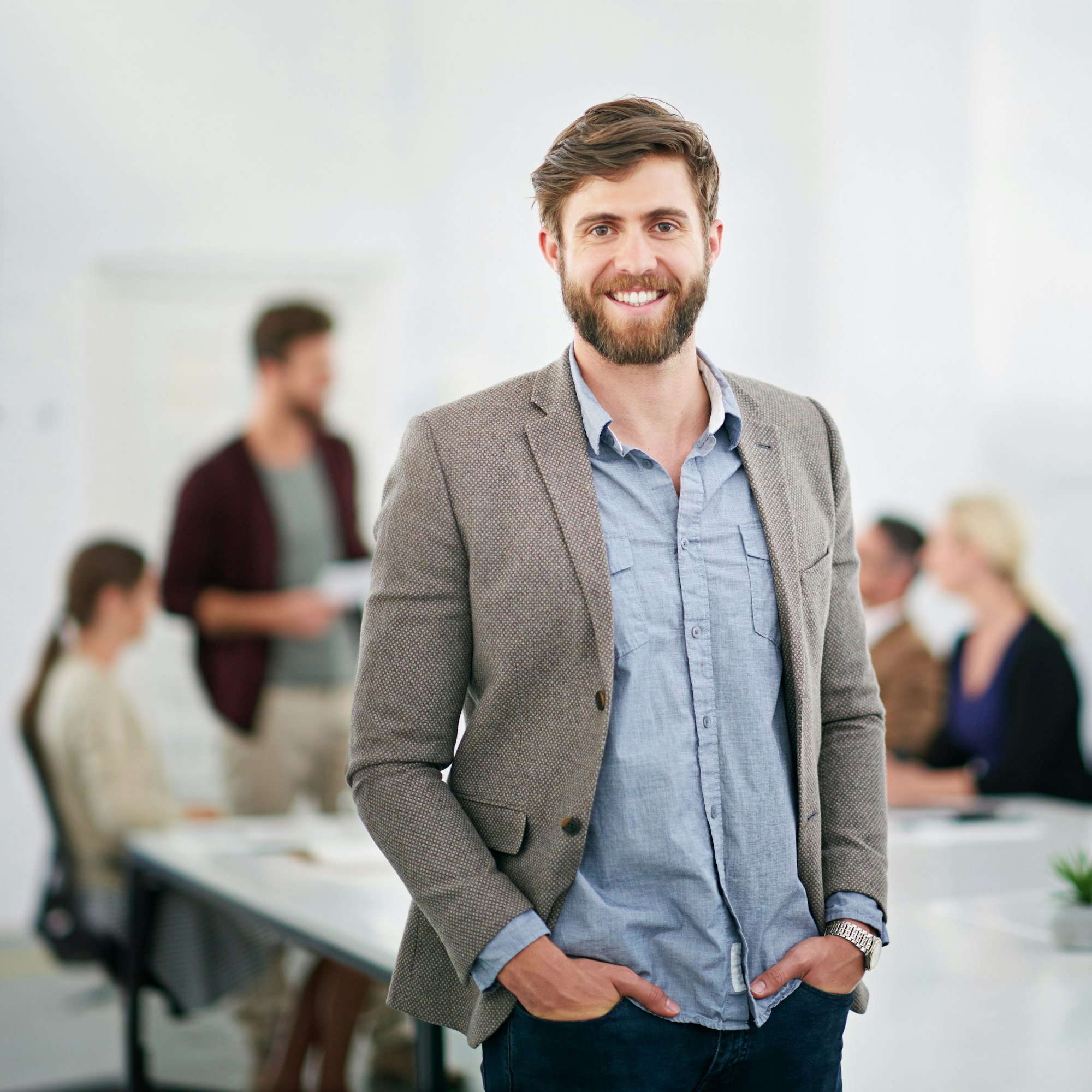 Portrait of a young businessman in an office with colleagues in the background