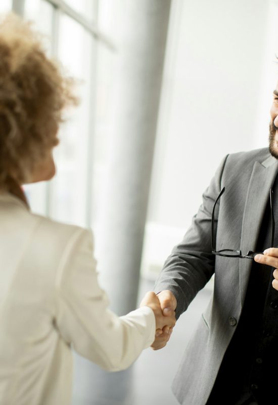 Couple of multiethnic business people handshaking in the office